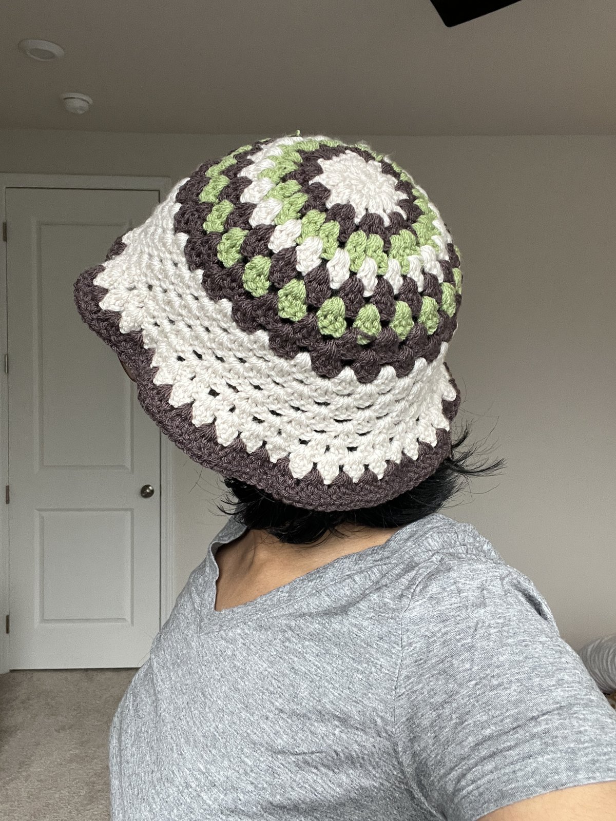 Bria wearing a cream, green and brown crocheted bucket hat
